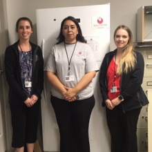 Three women standing in front of an upright freezer