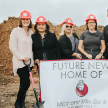 Group wearing hard hats standing at new construction site