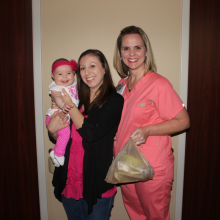 Mother holding baby, standing with nurse holding mom's milk donation