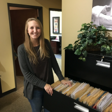 MMBNT staff standing by open filing cabinet