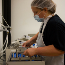 Lab technician removing tray of milk bottles from shaking water bath
