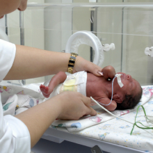 Premature baby being picked up by nurse