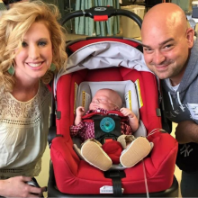 Mother and father posed around infant son, in carrier