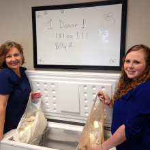 Mother and nurse posing with the mother's two grocery sacks of donated breastmilk
