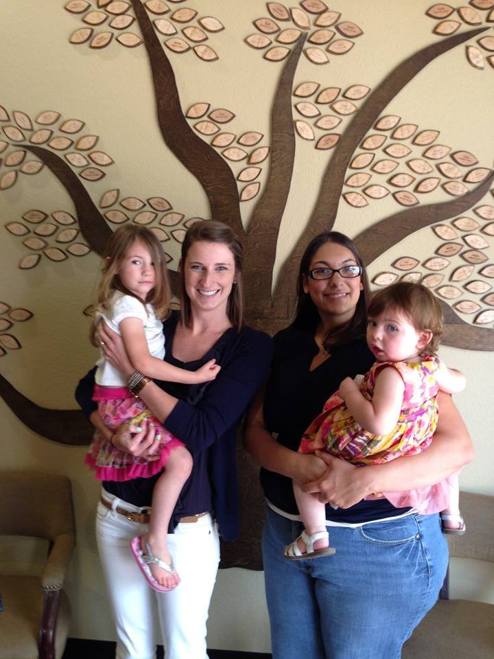 Two women, each holding a child