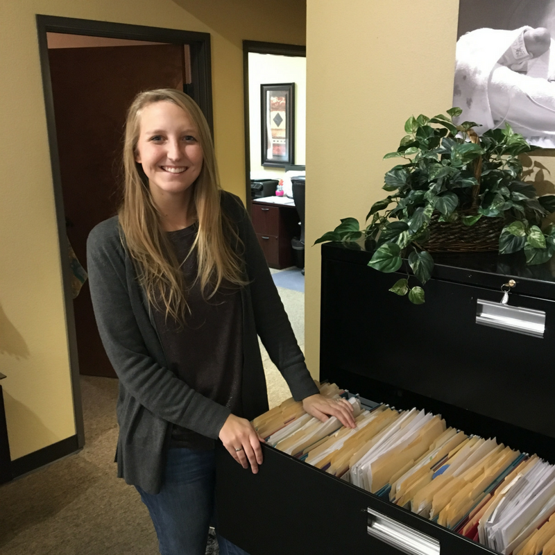 MMBNT staff standing by open filing cabinet