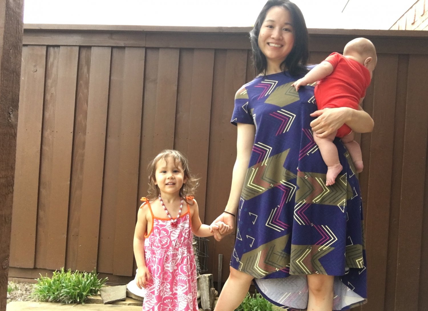 Mother holding infant son and holding hands with toddler daughter