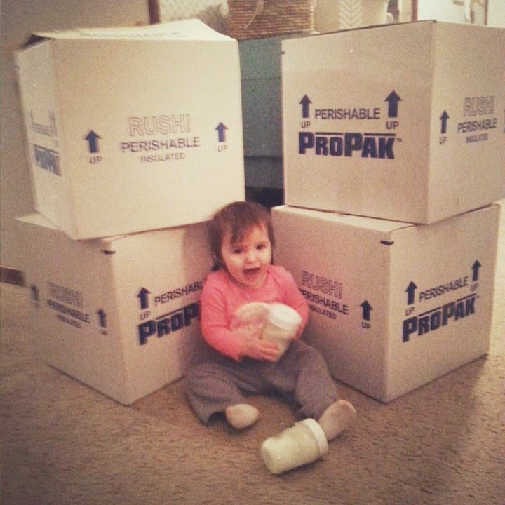 Baby sitting with coolers full of frozen breastmilk
