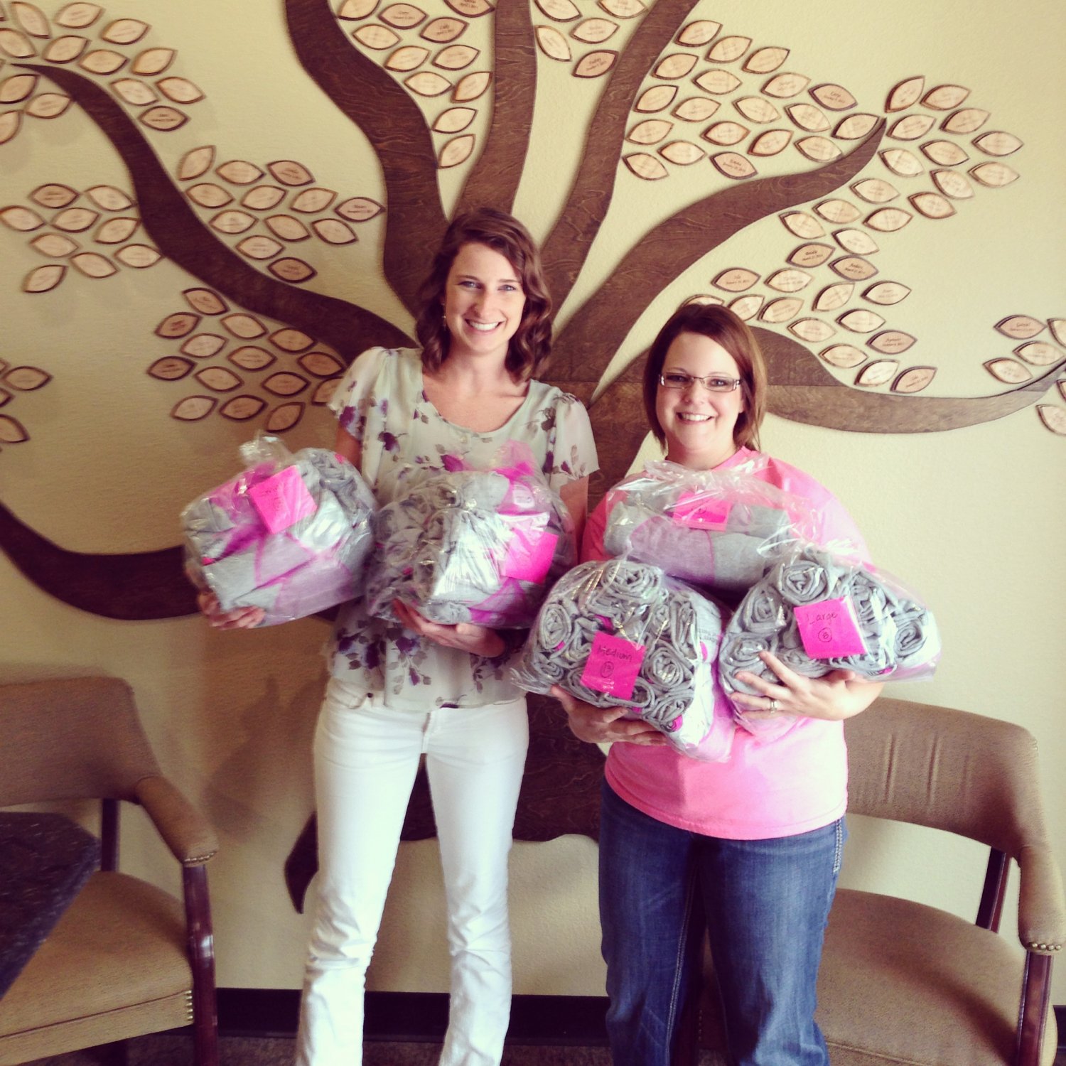 Two women holding bags of t shirts