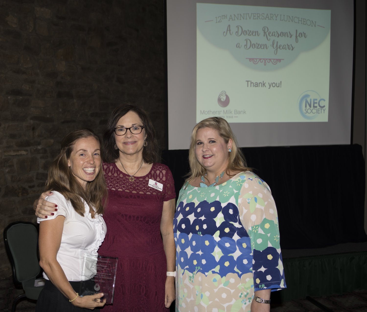 Three women standing in front of a presentation screen